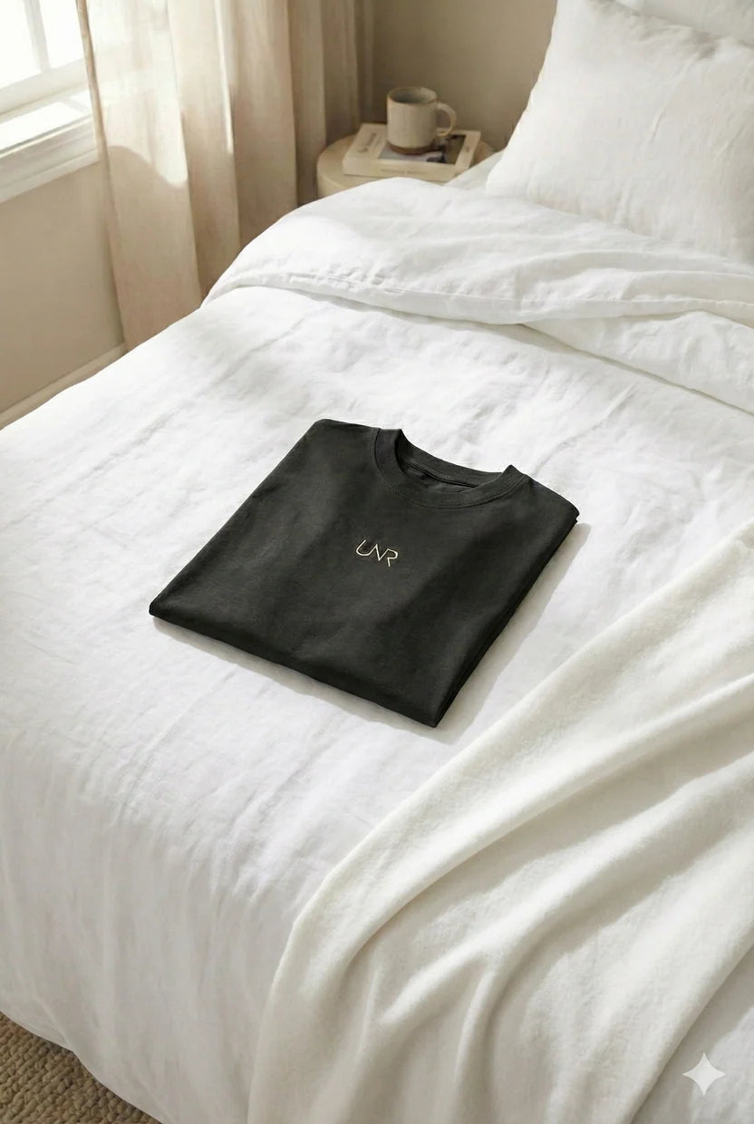 Black UNR Sorona Tee folded on a bed